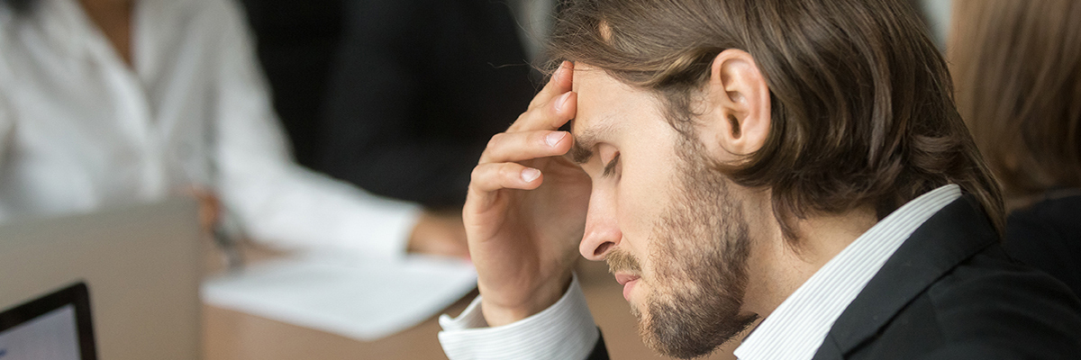 Frustrated tired businessman having strong headache at diverse team meeting
